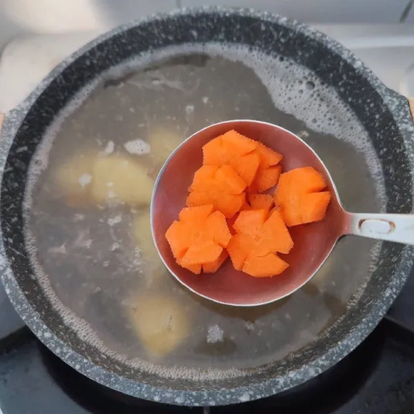 Setelah iga mulai empuk, masukkan potongan wortel dan kentang. Rebus hingga empuk.