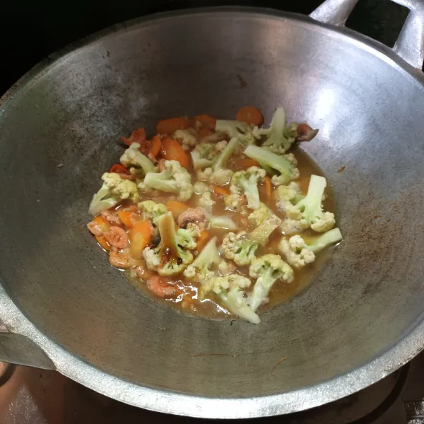 Lalu masukkan kembang kol, wortel dan air. Tambahkan saus tiram, kaldu jamur dan lada bubuk. Aduk dan biarkan sampai agak empuk.