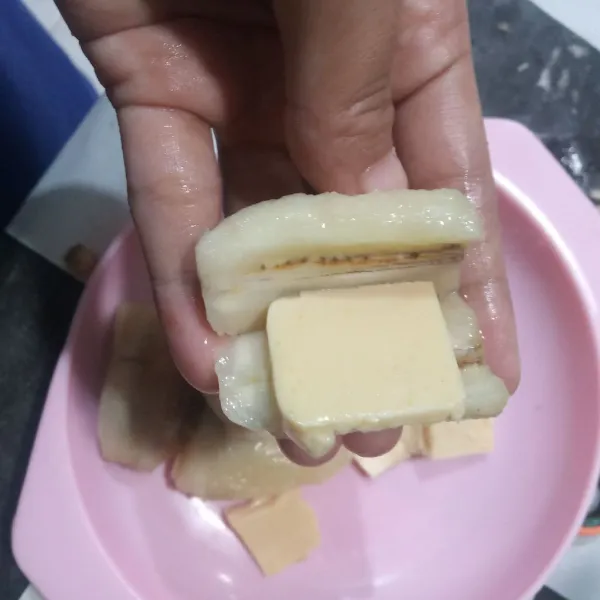 Belah pisang jangan sampai putus, masukkan potongan keju mozza ditengahnya.