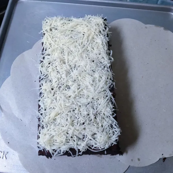 Oleskan selai coklat di atas cake, lalu taburi dengan keju parut, biarkan hingga set, dan siap untuk di sajikan.