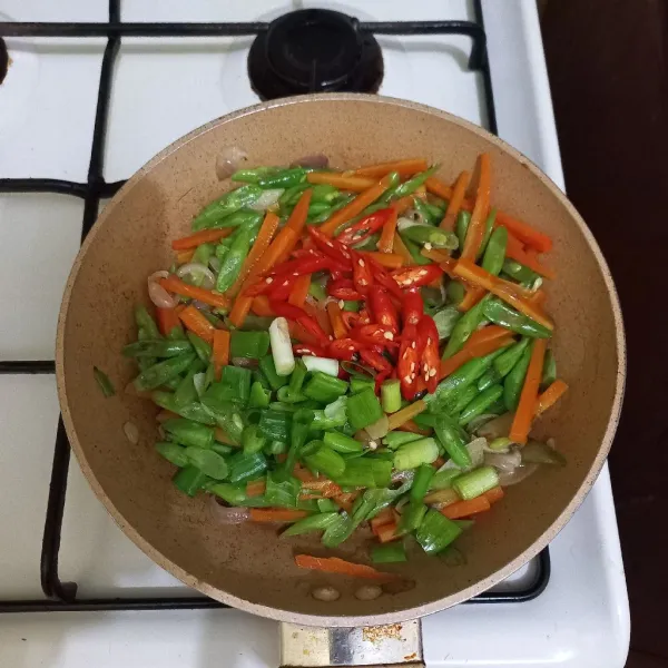 Masukan irisan bawang daun dan cabe merah keriting, masak hingga matang.