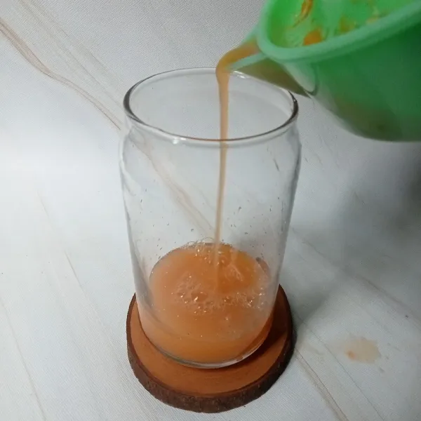 Peras jeruk dan ambil airnya, lalu tuang ke dalam gelas.