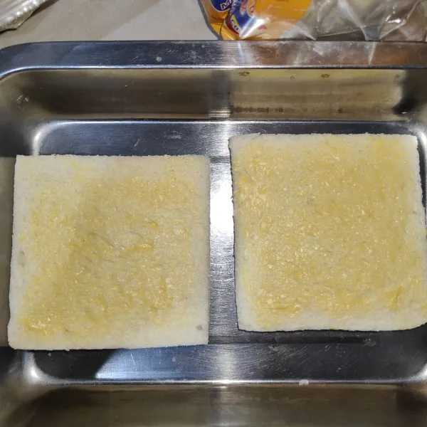 Olesi kedua sisi roti dengan margarin.