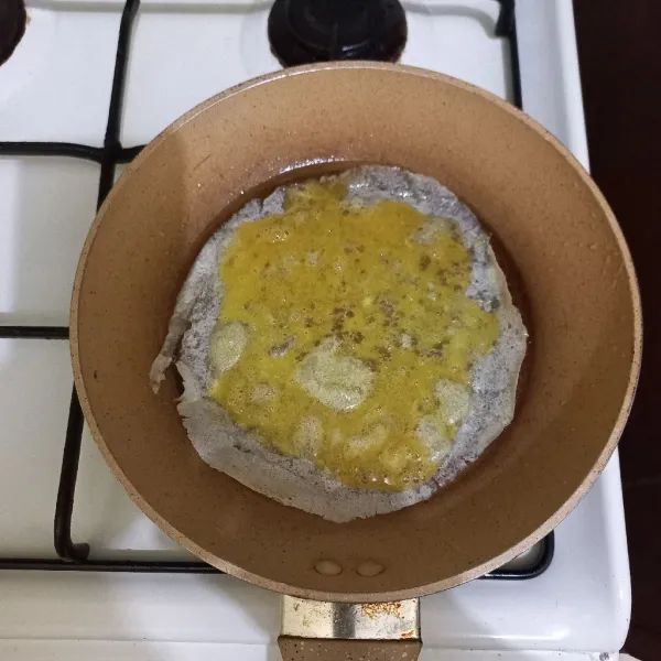 Panaskan teflon dengan api kecil dan minyak secukupnya, tata kulit lumpia di atasnya, tuang 1/3 bagian telur dan ratakan.