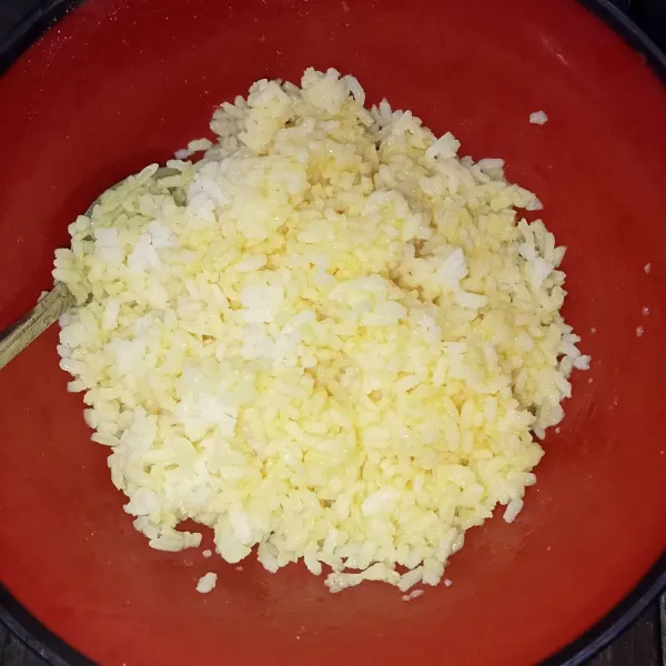 Masukkan nasi ke dalam kocokan telur dan aduk rata.