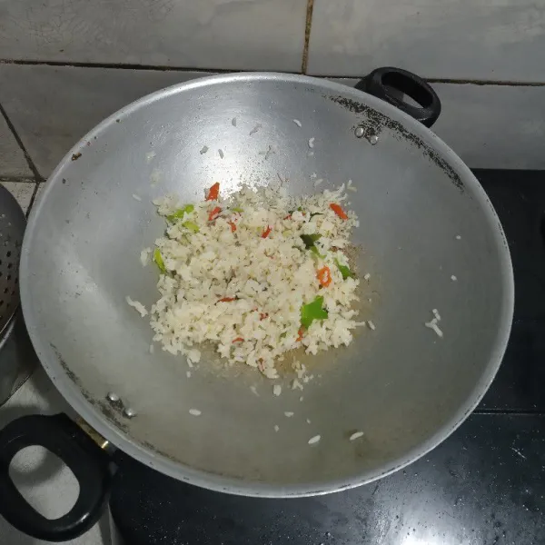 Masukan nasi, beri garam dan kaldu bubuk. Aduk rata.