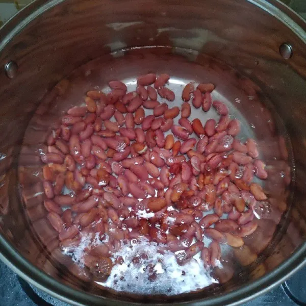 Rebus kacang sampai matang dan empuk, lalu buang air rebusan pertama.