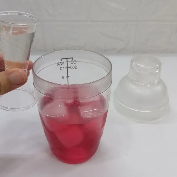 Tuang gelas shaker berisi es batu. Tuang air gula.