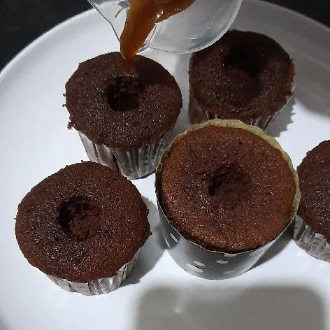 Setelah matang lubangi tengah cupcake dengan pangkal spuit lalu tuang saus caramel.