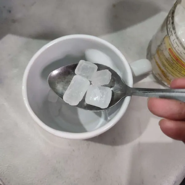 Tuang gula batu ke dalam gelas saji.