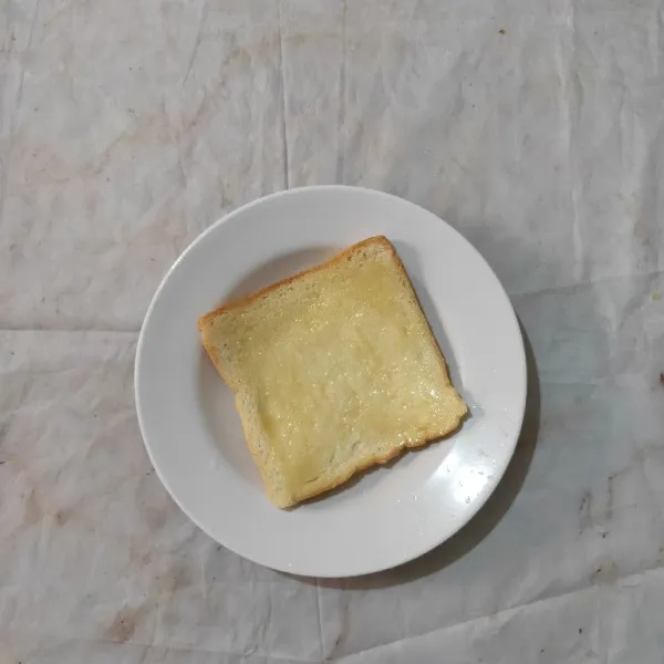 Siapkan roti tawar, kemudian oles dengan krimer kental manis.