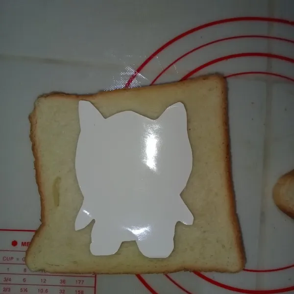Siapkan dua lembar roti letakkan karakter kartun diatasnya, lalu gunting roti menyesuaikan bentuk karakter.