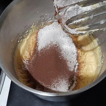 Masukkan tepung, baking soda dan coklat bubuk sambil di ayak lalu mixer hingga rata.