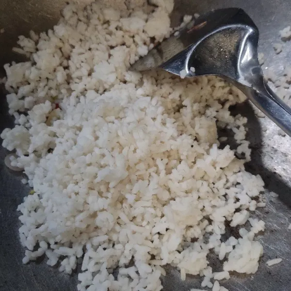 Masukkan nasi, beri garam dan penyedap rasa. Aduk rata.