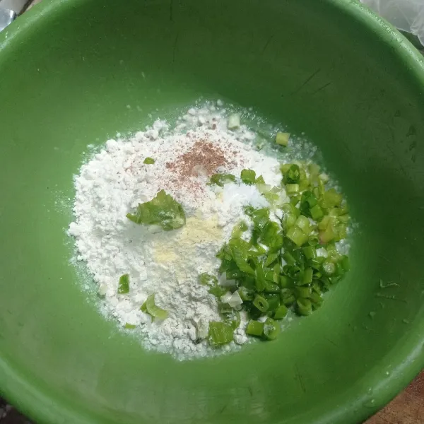 Masukkan tepung terigu, garam, kaldu bubuk, ketumbar bubuk, dan irisan daun bawang ke dalam wadah.