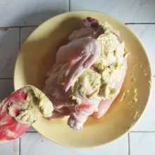 Masukkan campuran mentega ke dalam sela kulit ayam dan ratakan. Masukkan juga potongan lemon, rosemary, dan bawang putih utuh ke bawah tubuh ayam.