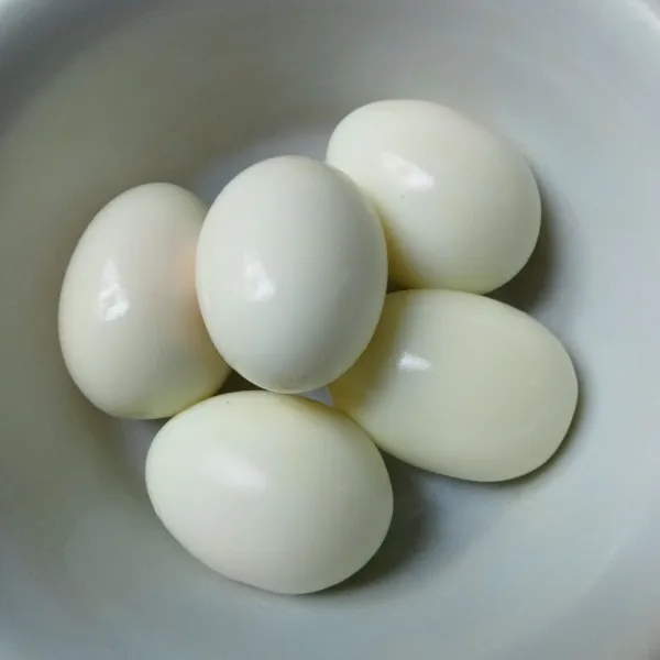 Rebus telur sampai matang, lalu kupas kulitnya.