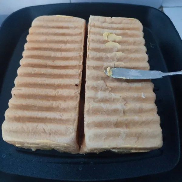 Panaskan teflon, panggang roti bagian tengah terlebih dahulu sampai kecoklatan sambil bagian luar dioles margarin secara merata.