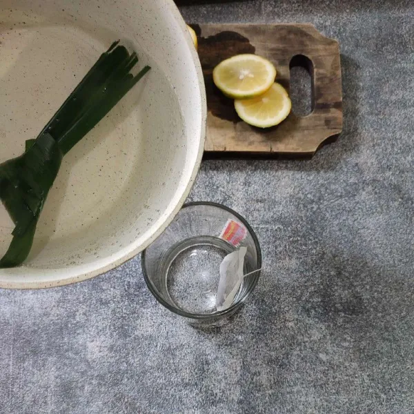 Tuang air rebusan pandan ke dalam gelas berisi teh celup.