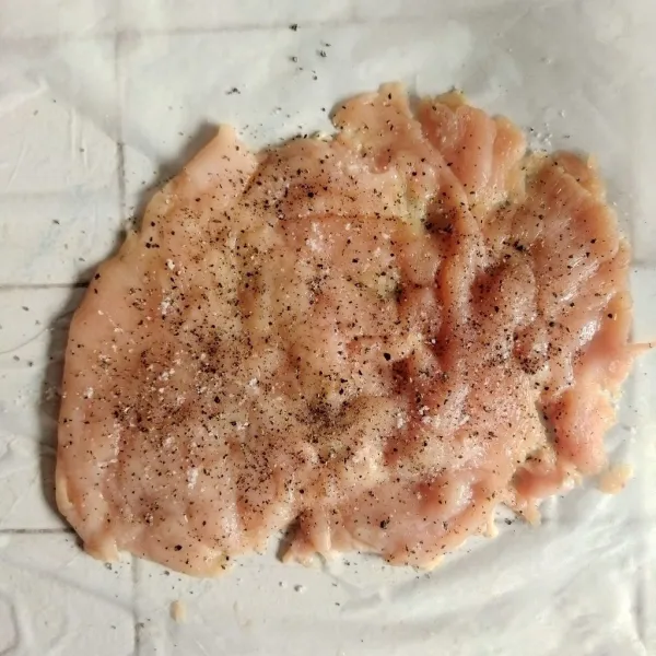 Siapkan satu buah dada ayam lalu sayat menjadi dua bagian dan memarkan dengan meat hammer hingga lebih lebar. Taburkan garam, bawang putih bubuk dan lada ke bagian masing-masing permukaan ayam.