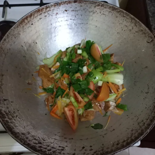 Masukkan irisan tomat dan daun bawang, masak hingga matang.