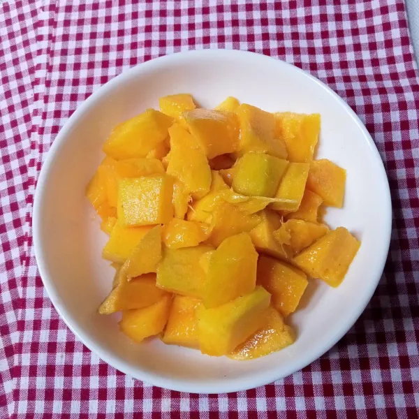 Kupas buah mangga dan potong-potong.