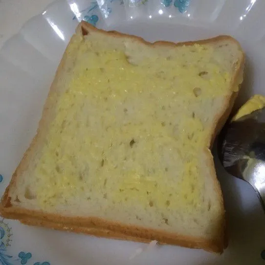Oles di setiap sisi atas dan bawah roti tawar dengan margarin secara merata.