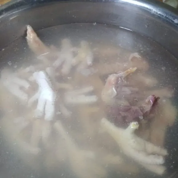 Buat kuah mie ayam rebus tulang dan cakar ayam, buang busa yang muncul kemudian tambahkan lada, garam dan potongan daun bawang.