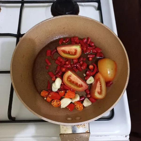 Panaskan minyak goreng, goreng hingga layu cabe rawit, cabe merah keriting, bawang putih dan tomat.