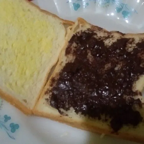 Diatas tumpukan roti tawar, oles dengan selai coklat cruncy, dan ambil lembar roti tawar ketiga kemudian oles dengan margarin dan tumpuk.