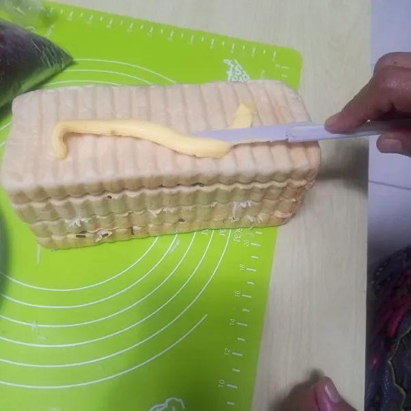 Oles bagian luar roti dengan margarin.