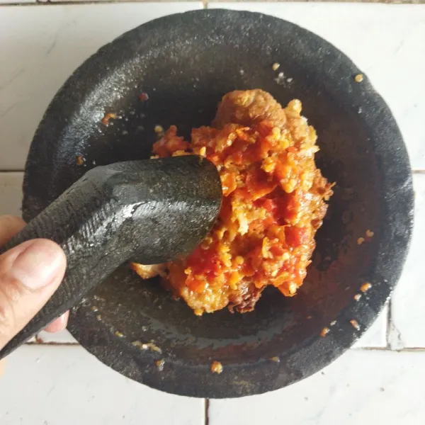 Letakkan ayam goreng tepung di atas sambal yang telah dihaluskan. Lalu geprek ayam hingga seratnya terpecah agar sambal merata. Sajikan dengan nasi dan lalapan.
