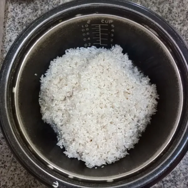 Cuci bersih beras, tuang pada panci rice cooker.