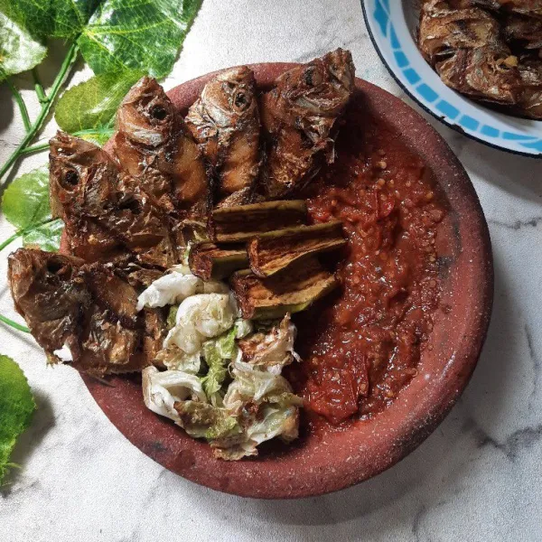 Sajikan lalapan ikan goreng dengan terong dan kol goreng.