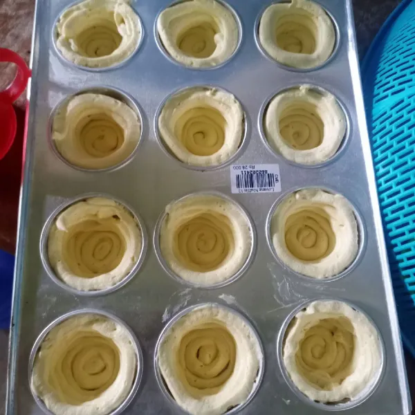 Siapkan cetakan muffin yang sudah dioles margarin. Semprotkan adonan secara melingkar membentuk mangkuk mulai dari dasar cetakan sampai ke atas.