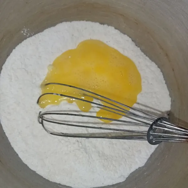 Tuang telur ke dalam wadah tepung.