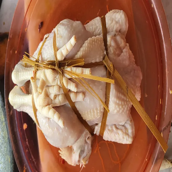 Masukkan jeroan yang sudah dicampur bumbu kedalam ayam, tambahkan selembar daun salam kemudian ikat ayam agar jeroan tidak keluar