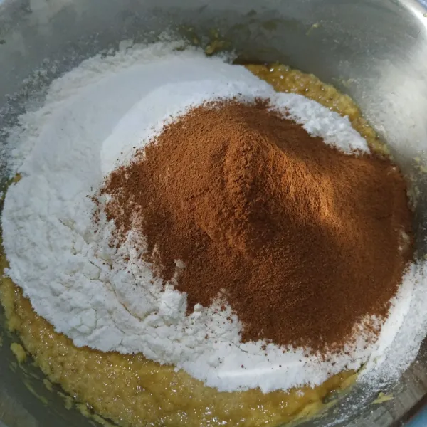 Ayak tepung terigu, garam, baking powder, kayu manis bubuk dan rempah bubuk di atas adonan.