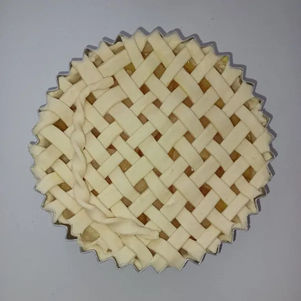 Letakkan pastry yang sudah dipotong memanjang di atas loyang pie dan bentuk menyerupai jaring.