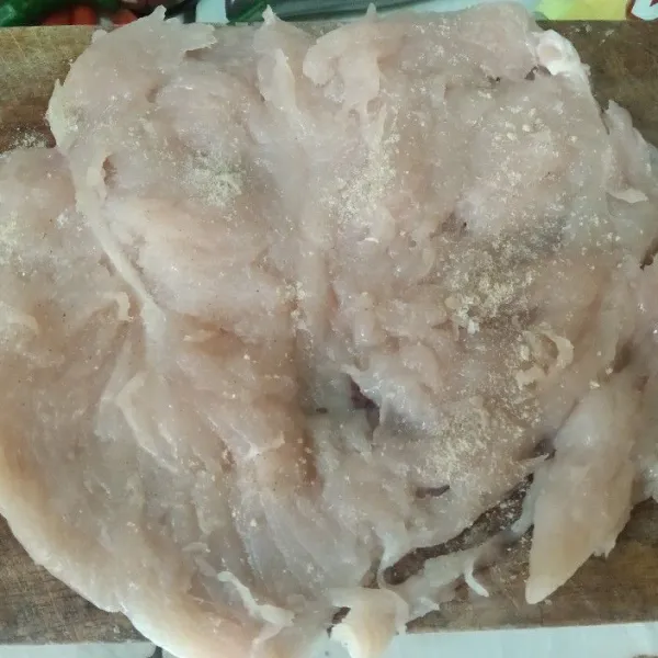 Belah ayam fillet, pukul pukul ayam dengan alat pengempuk daging, lalu taburi garam dan lada bubuk ratakan setiap sisi bagian ayam.