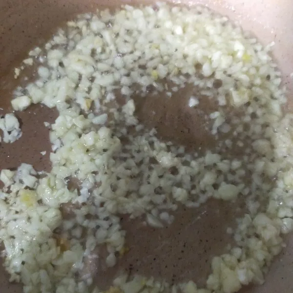 Panaskan minyak, kemudian tumis bawang putih cincang hingga harum dan kecoklatan, angkat dan sisihkan.