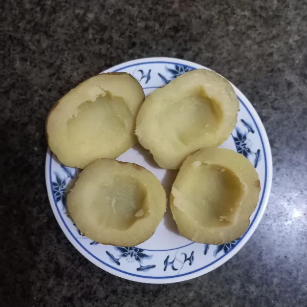 Kerok bagian tengah kentang dengan bantuan sendok.