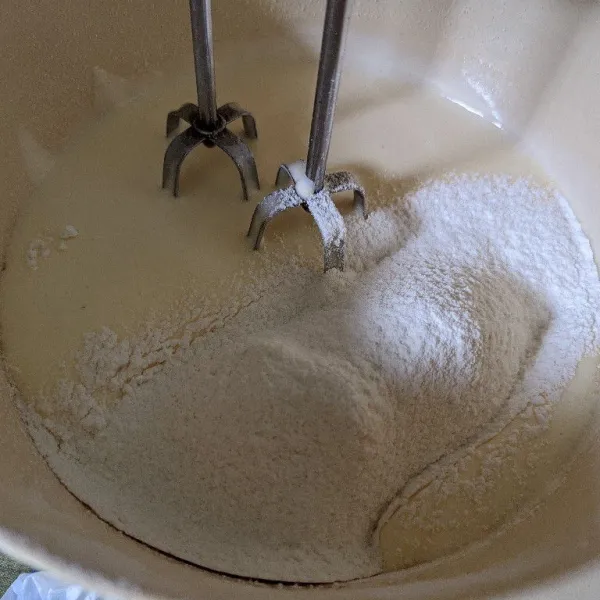 Masukkan susu bubuk dan tepung terigu bertahap dengan cara di ayak, mixer dengan kecepatan rendah.