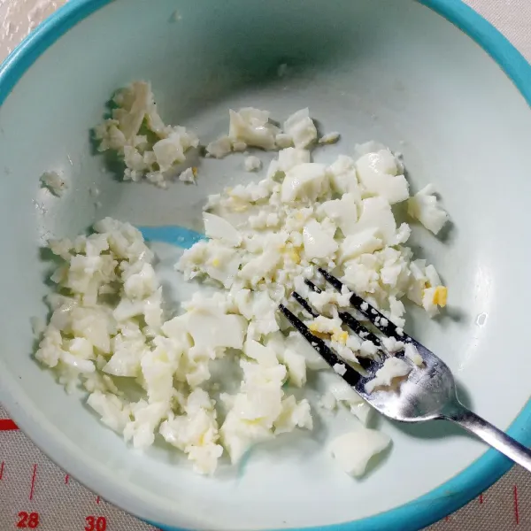 Di wadah hancurkan putih telur rebus menggunakan garpu. Masukkan juga ke alpukat, aduk asal saja. Cek rasa.