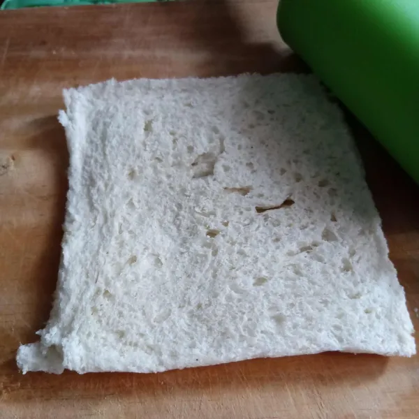 Ambil selembar roti tawar, gilas dengan rolling pin. Lakukan hingga semua roti tergilas.