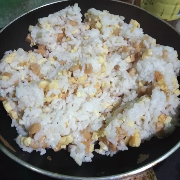 Campurkan nasi, sosis, telur, dan kaldu ayam bubuk hingga rata, sambil dihangatkan.