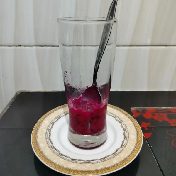 Masukkan buah naga ke dalam gelas lalu kocok dengan sendok hingga hancur kasar.
