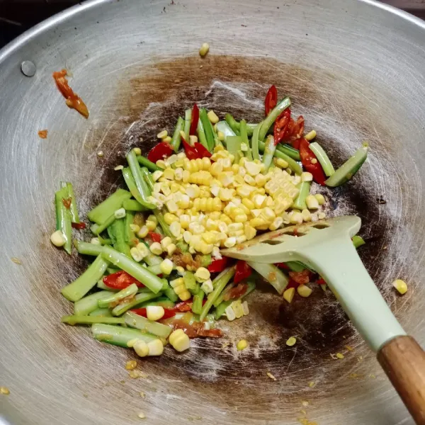 Masukkan irisan cabe merah, batang sawi dan jagung, aduk rata. Kemudian tuang air, biarkan mendidih.