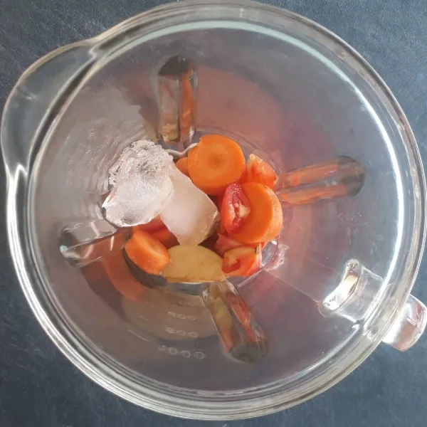 Masukkan buah apel, wortel, tomat, dan es batu ke dalam blender.
