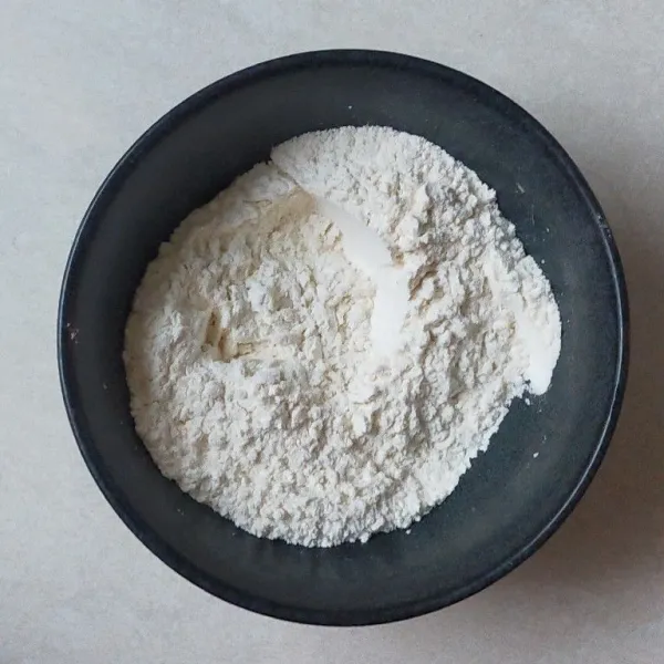 Di dalam mangkuk, ayak tepung terigu dan tepung beras. Kemudian tambahkan gula pasir, baking powder, dan baking soda, lalu aduk.